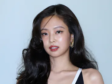 Jennie at the Chanel show in Seoul, standing against a wall