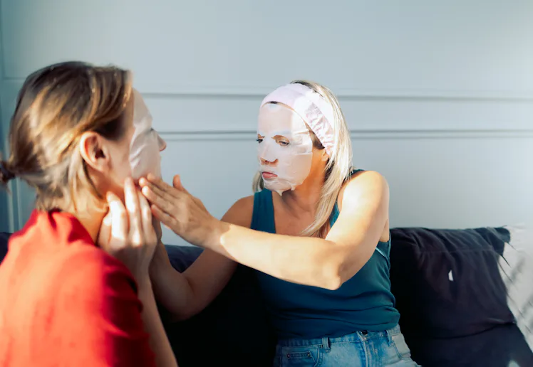 Women friends uses a cosmetic sheet face mask at home