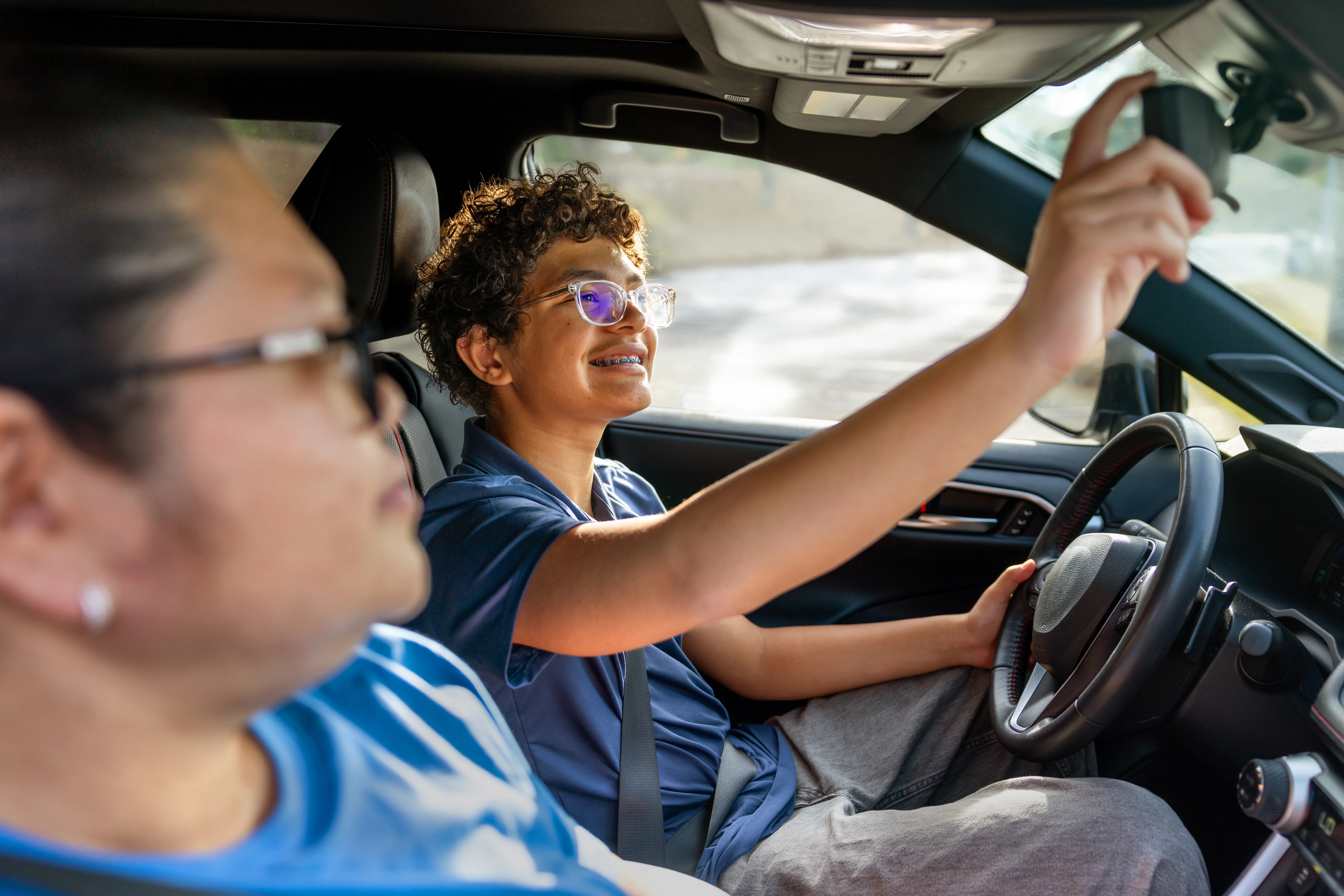 A Fillipino American teaching her multiracial son how to drive.