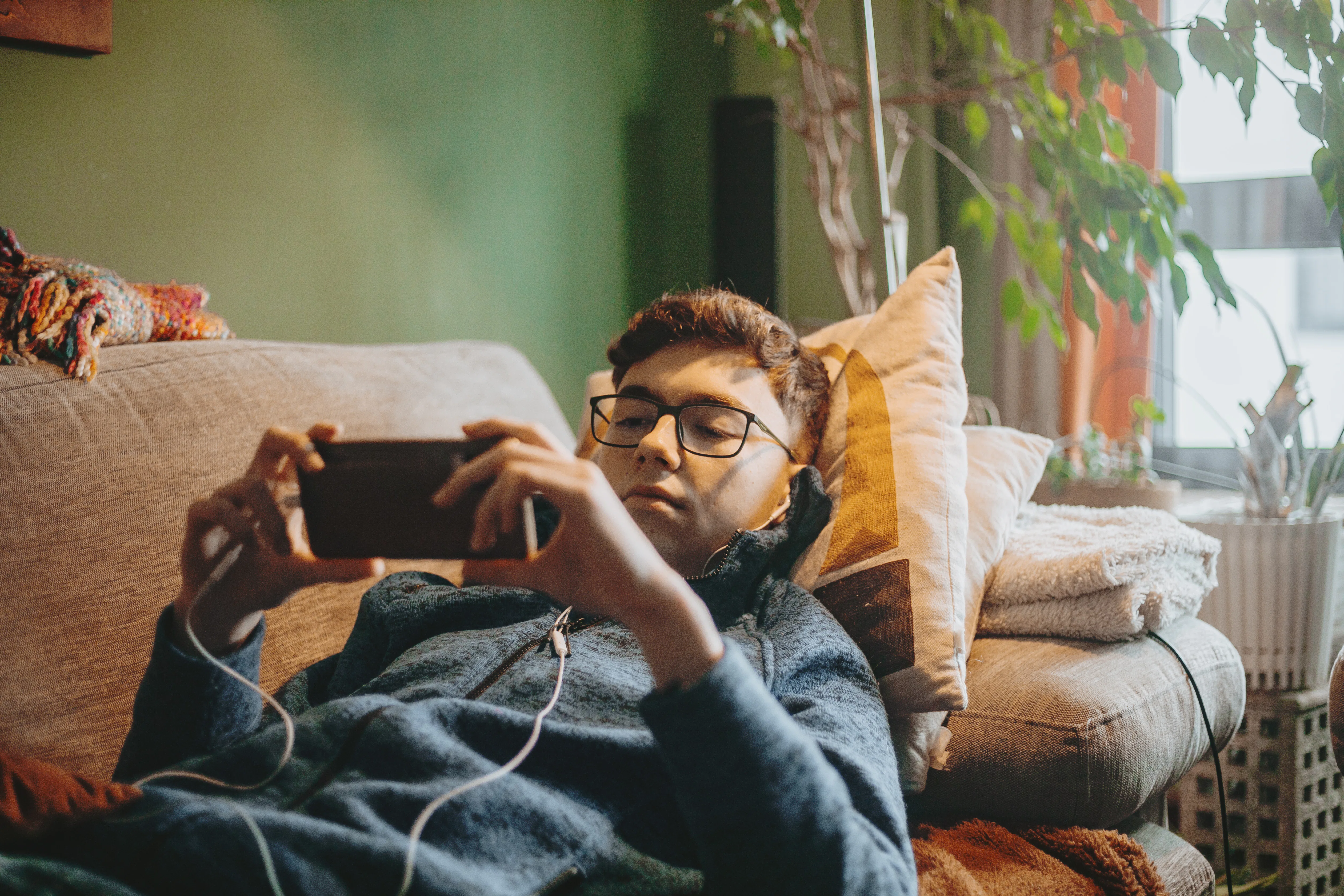 social media addicted teenage boy using mobile phone sitting on carpet