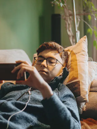 social media addicted teenage boy using mobile phone sitting on carpet
