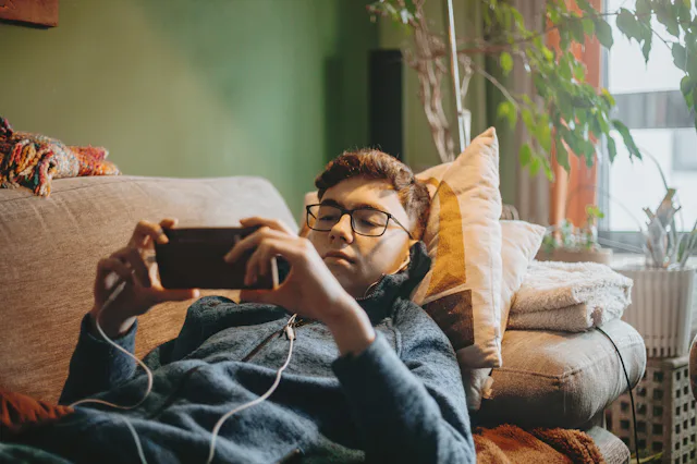 social media addicted teenage boy using mobile phone sitting on carpet