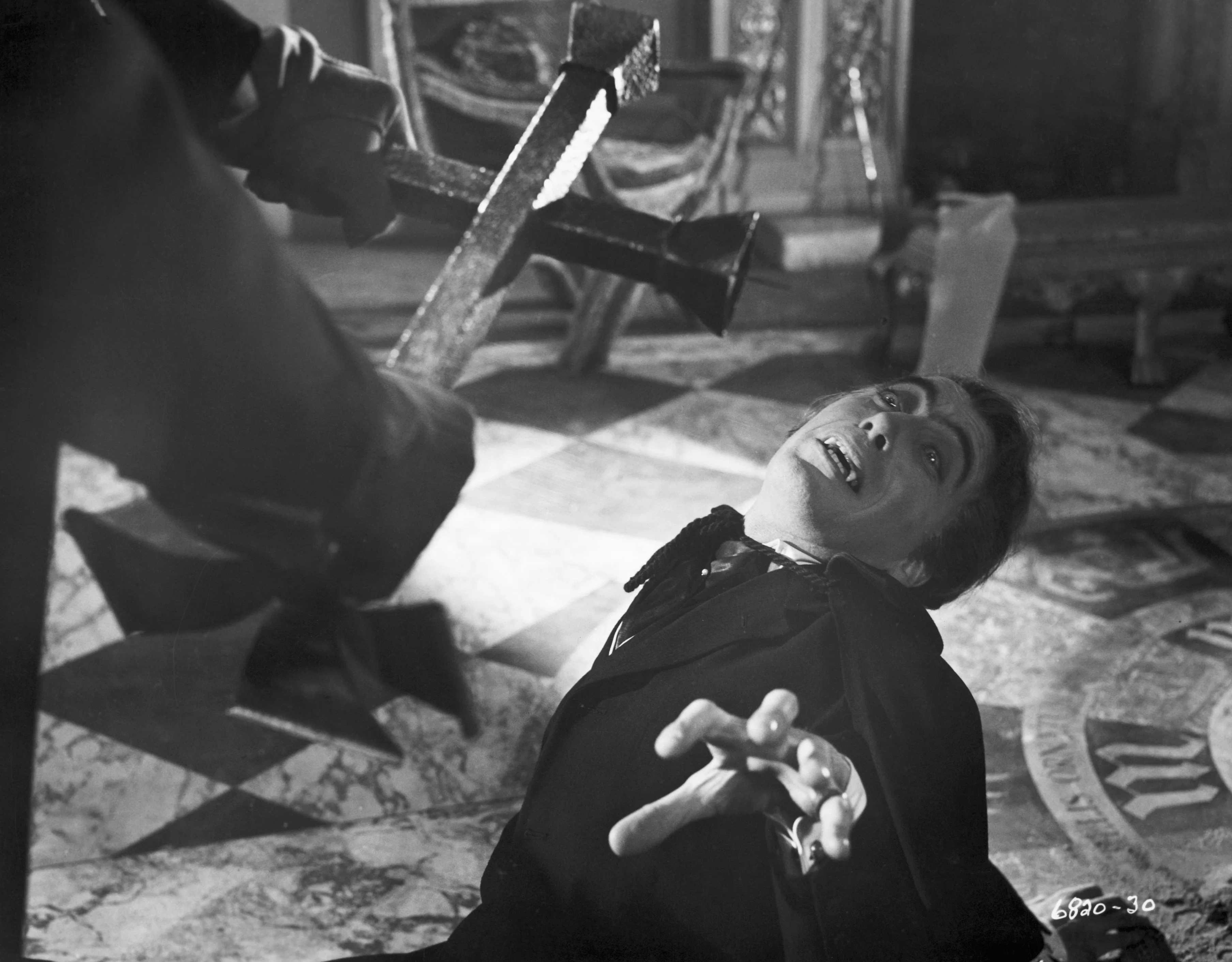 (Original Caption) 1958- Dracula, the human vampire, is shown cringing before the crucifix, is force...