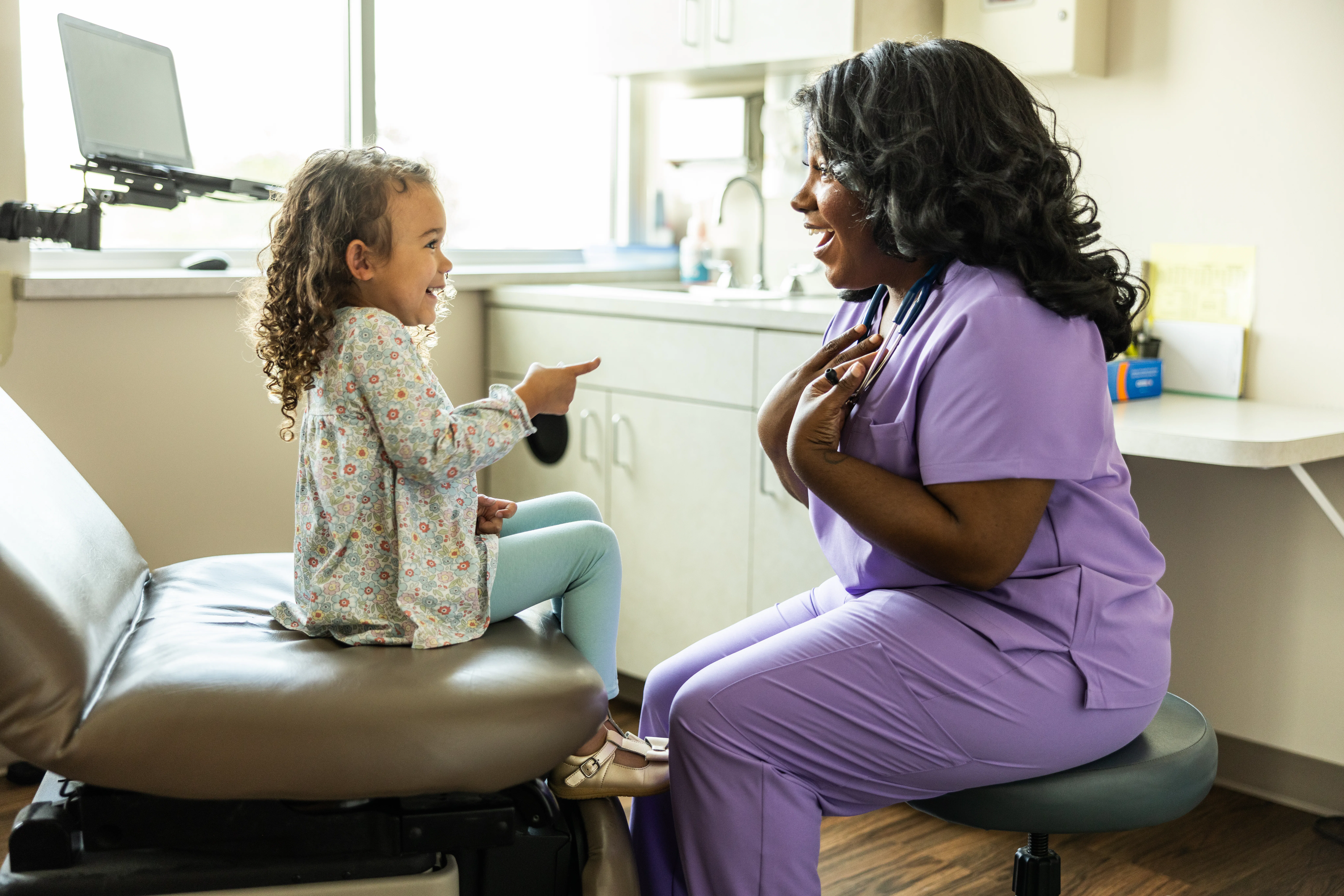 Female nurse talking with young girl in medical office