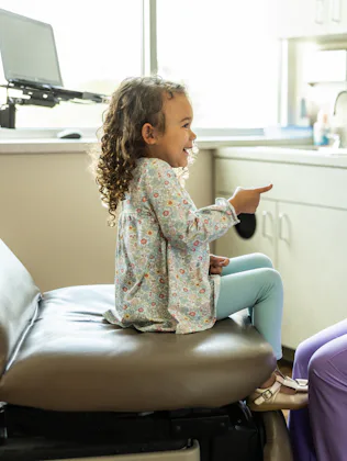 Female nurse talking with young girl in medical office