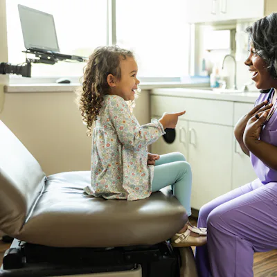 Female nurse talking with young girl in medical office