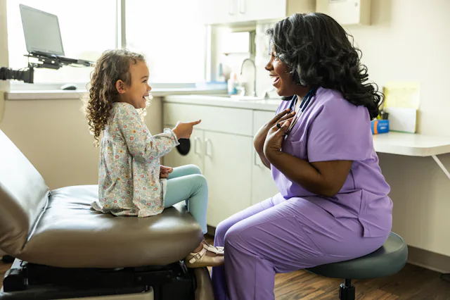 Female nurse talking with young girl in medical office
