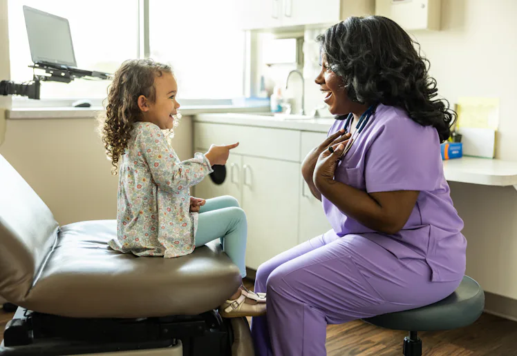 Female nurse talking with young girl in medical office