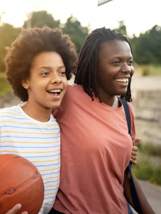 Embraced mother and daughter of Black ethnicity, going home after they finished with outdoor basketb...
