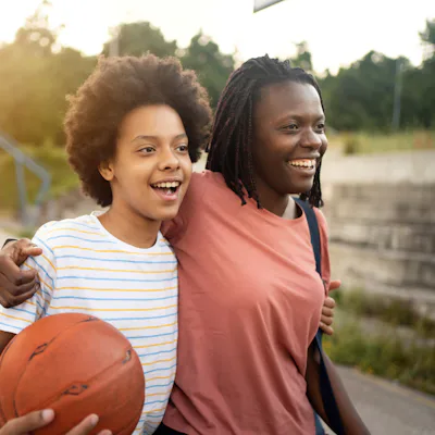 Embraced mother and daughter of Black ethnicity, going home after they finished with outdoor basketball recreational pursuit