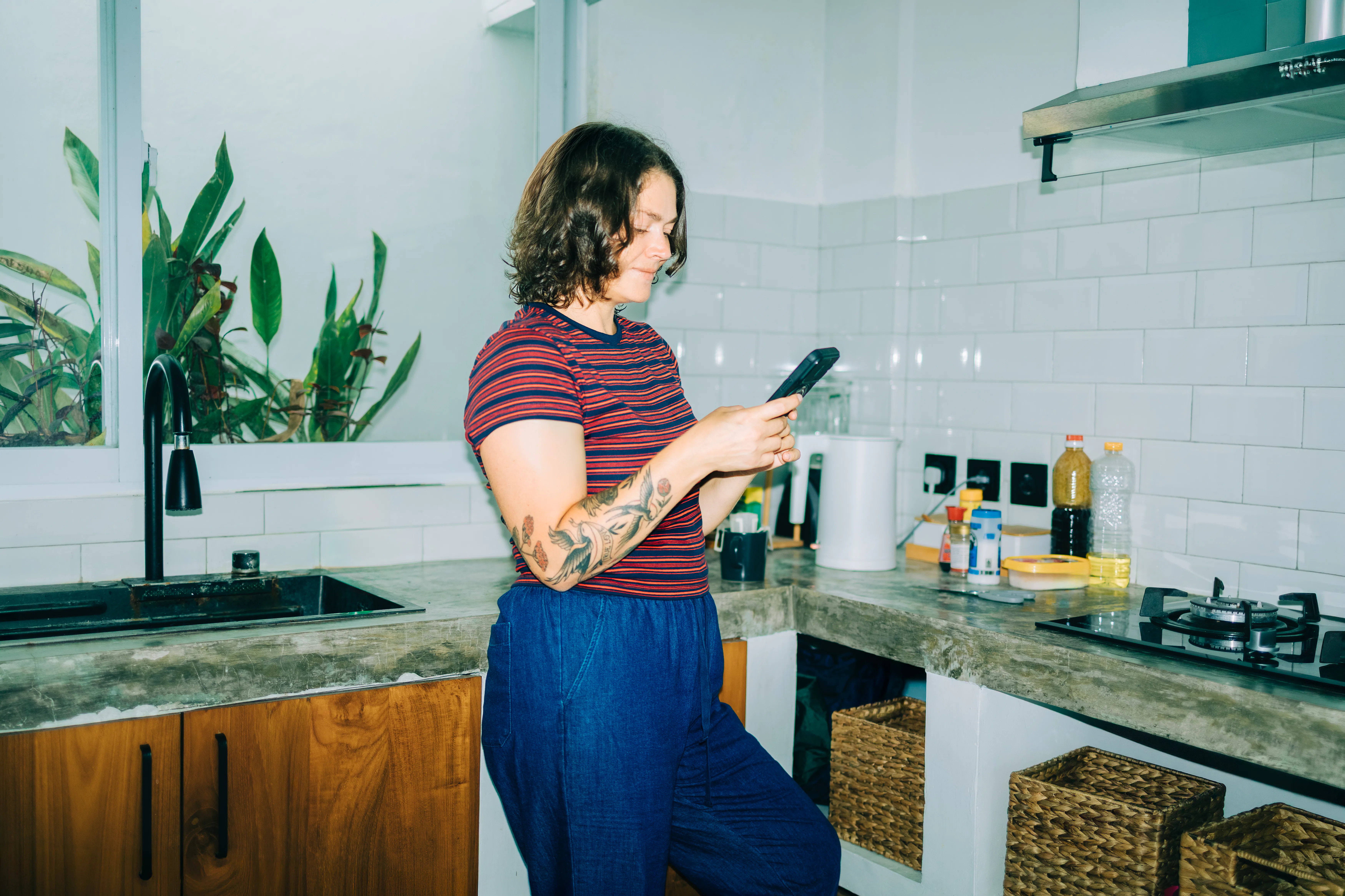 Woman smiling using smartphone in kitchen
