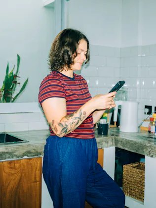 Woman smiling using smartphone in kitchen
