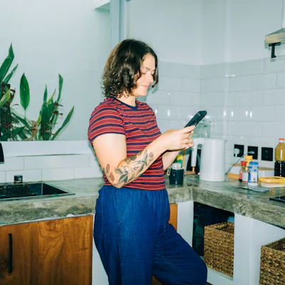 Woman smiling using smartphone in kitchen