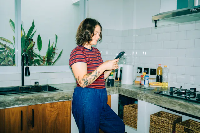 Woman smiling using smartphone in kitchen