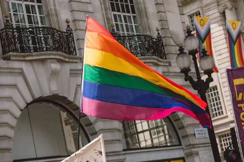 Rainbow pride flag waving in the air during an LGBT public event in Piccadilly Circus, London, Engla...