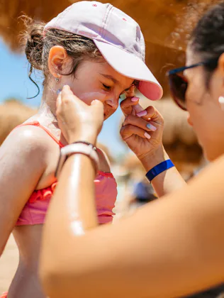 Young mother putting sunscreen on her daughter on the beach in Hurghada in Egypt.