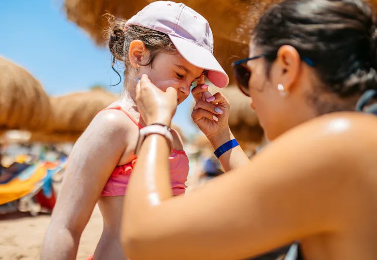 Young mother putting sunscreen on her daughter on the beach in Hurghada in Egypt.