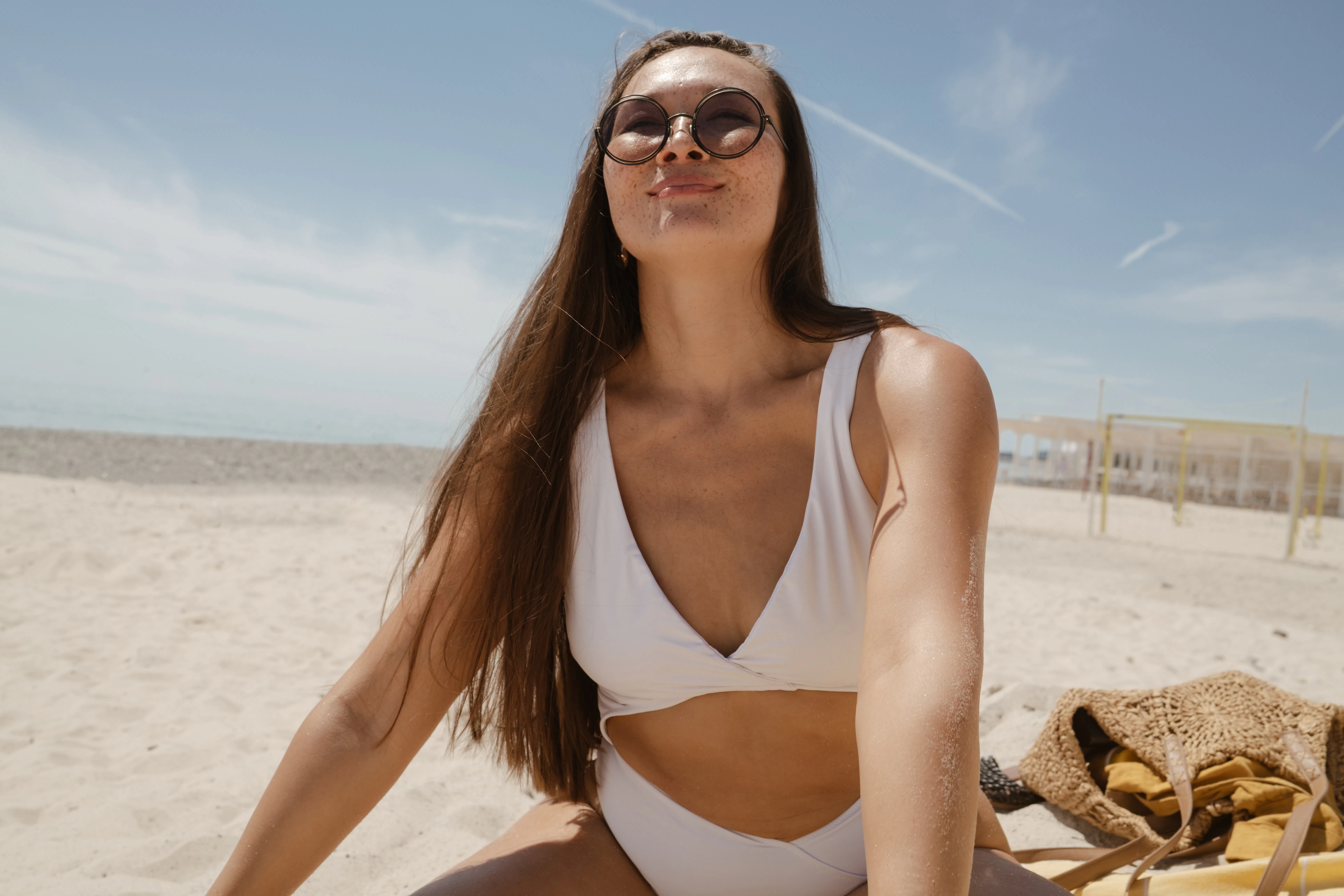 Close-up lifestyle portrait of a cheerful freckled woman enjoying a relaxing day by the sea. Wearing...