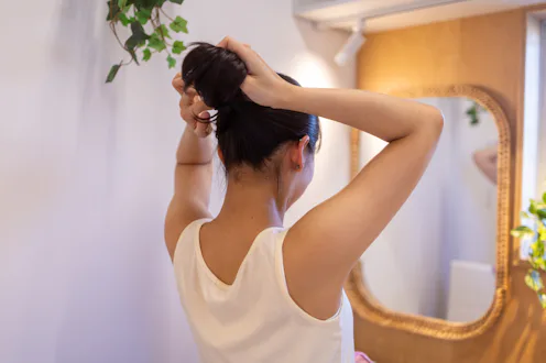 Young woman setting up her hair in bathroom