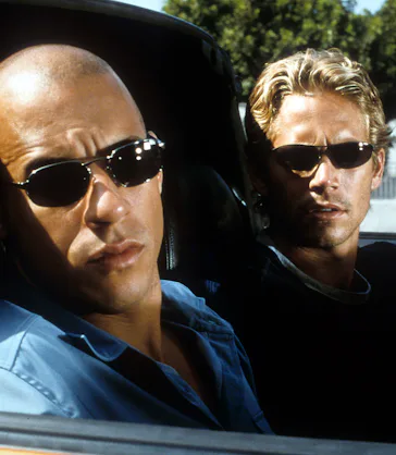 Vin Diesel and Paul Walker looking from car in a scene from the film 'The Fast And The Furious', 200...