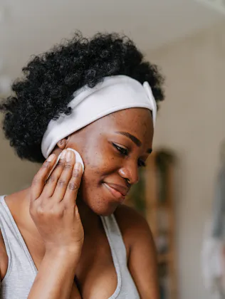 Photo of a young African American woman cleaning her skin with a tonic before going to sleep