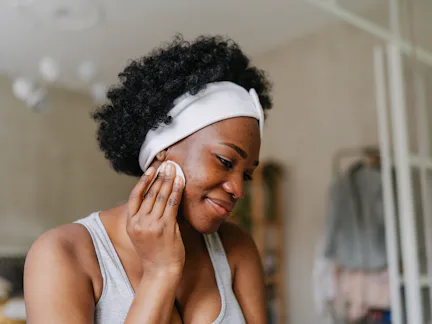 Photo of a young African American woman cleaning her skin with a tonic before going to sleep