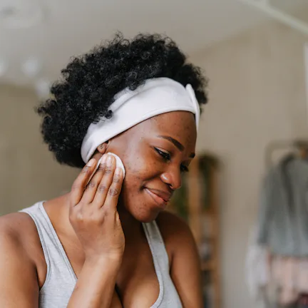 Photo of a young African American woman cleaning her skin with a tonic before going to sleep