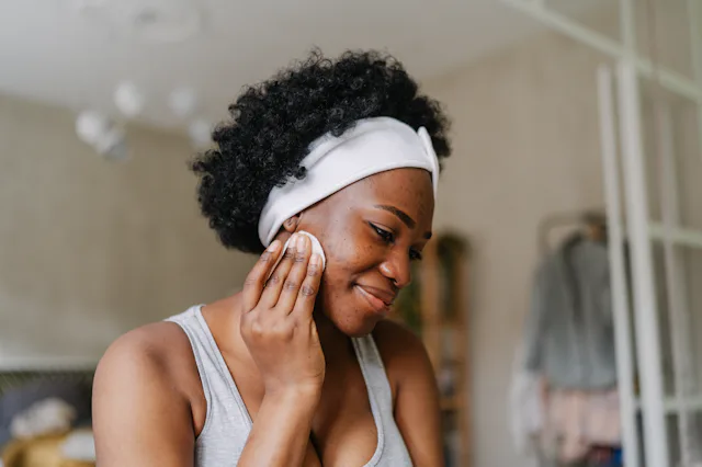 Photo of a young African American woman cleaning her skin with a tonic before going to sleep