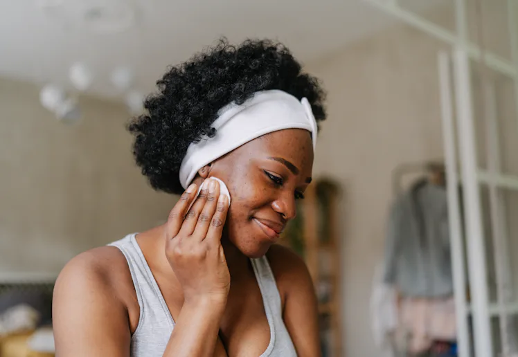 Photo of a young African American woman cleaning her skin with a tonic before going to sleep