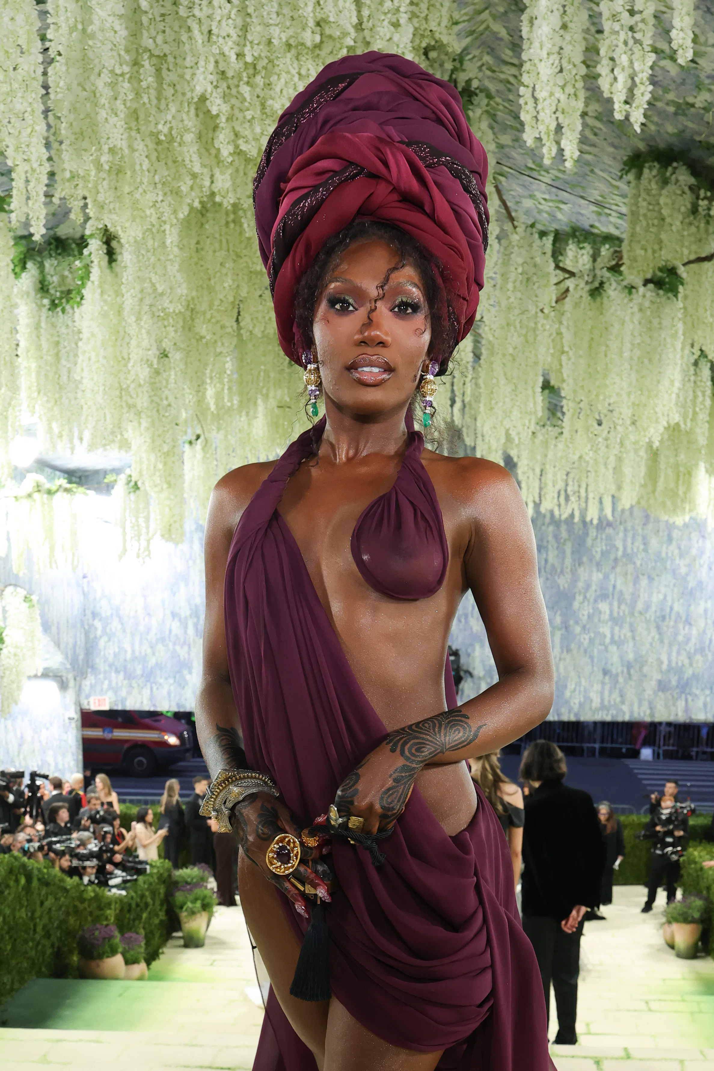 Doechii at the Met Gala with a beautiful turban and wine-colored dress