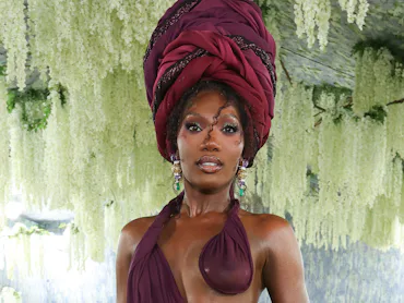 Doechii at the Met Gala with a beautiful turban and wine-colored dress
