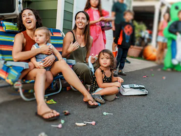 A multiracial group of kids and adults gather along the road in front of their homes in Hawaii as a ...