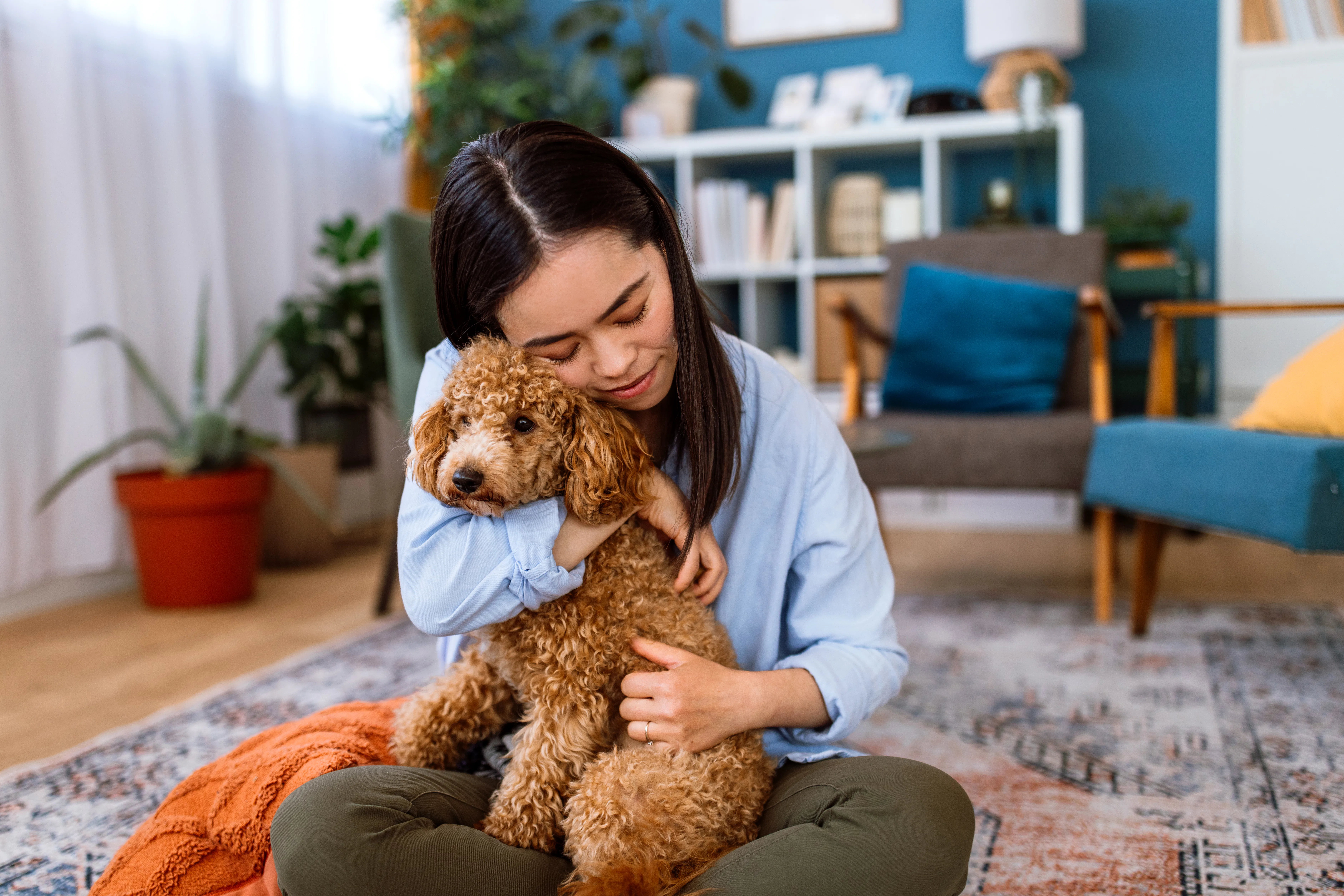 A woman enjoying quality time with her dog, showing affection while sitting in a comfortable home en...