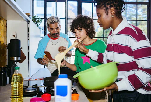 Diverse gen z friends preparing food, making pancakes, enjoying social gathering at home