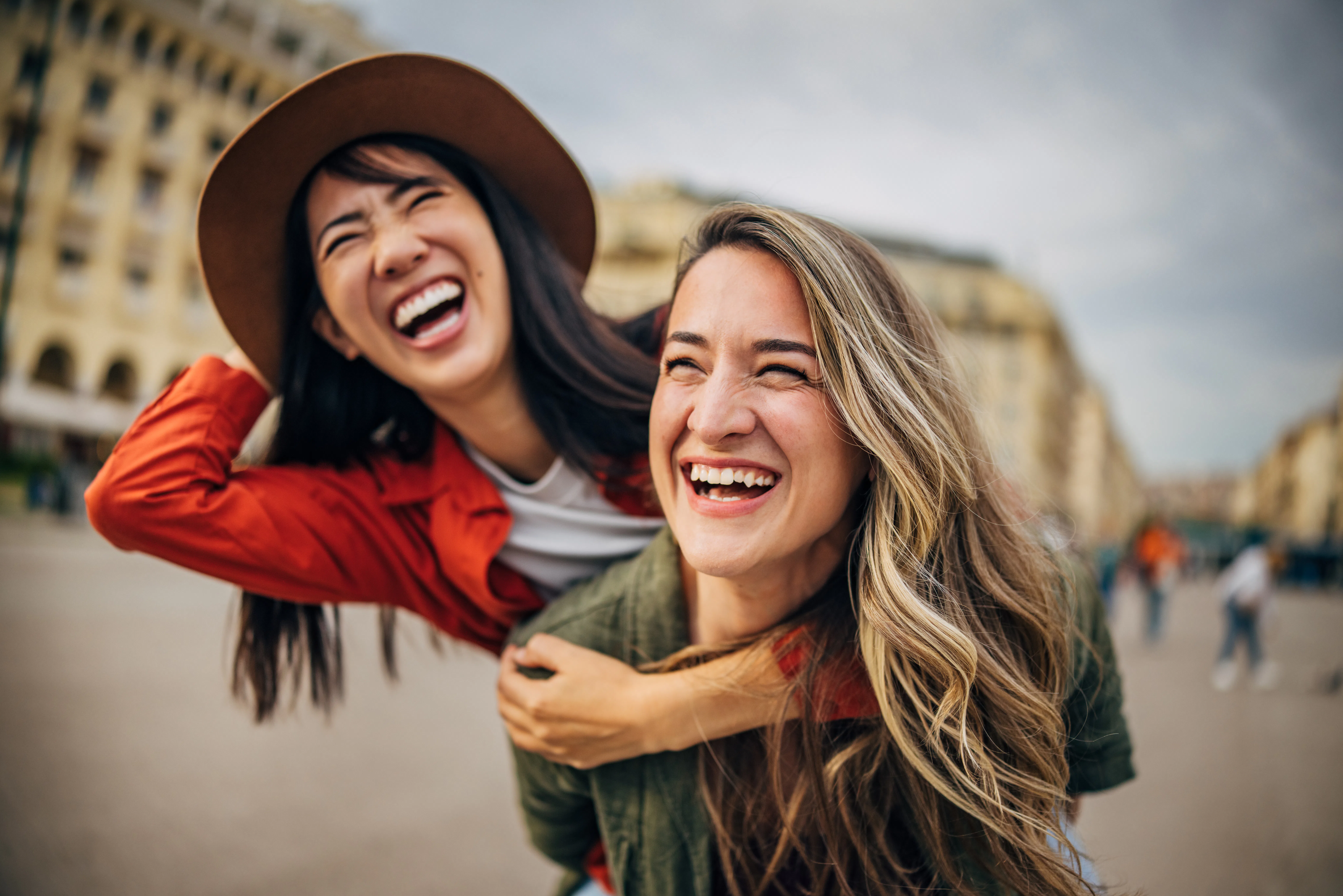 Two women share a joyful moment in Thessaloniki, Greece. They smile and laugh as one gives the other...