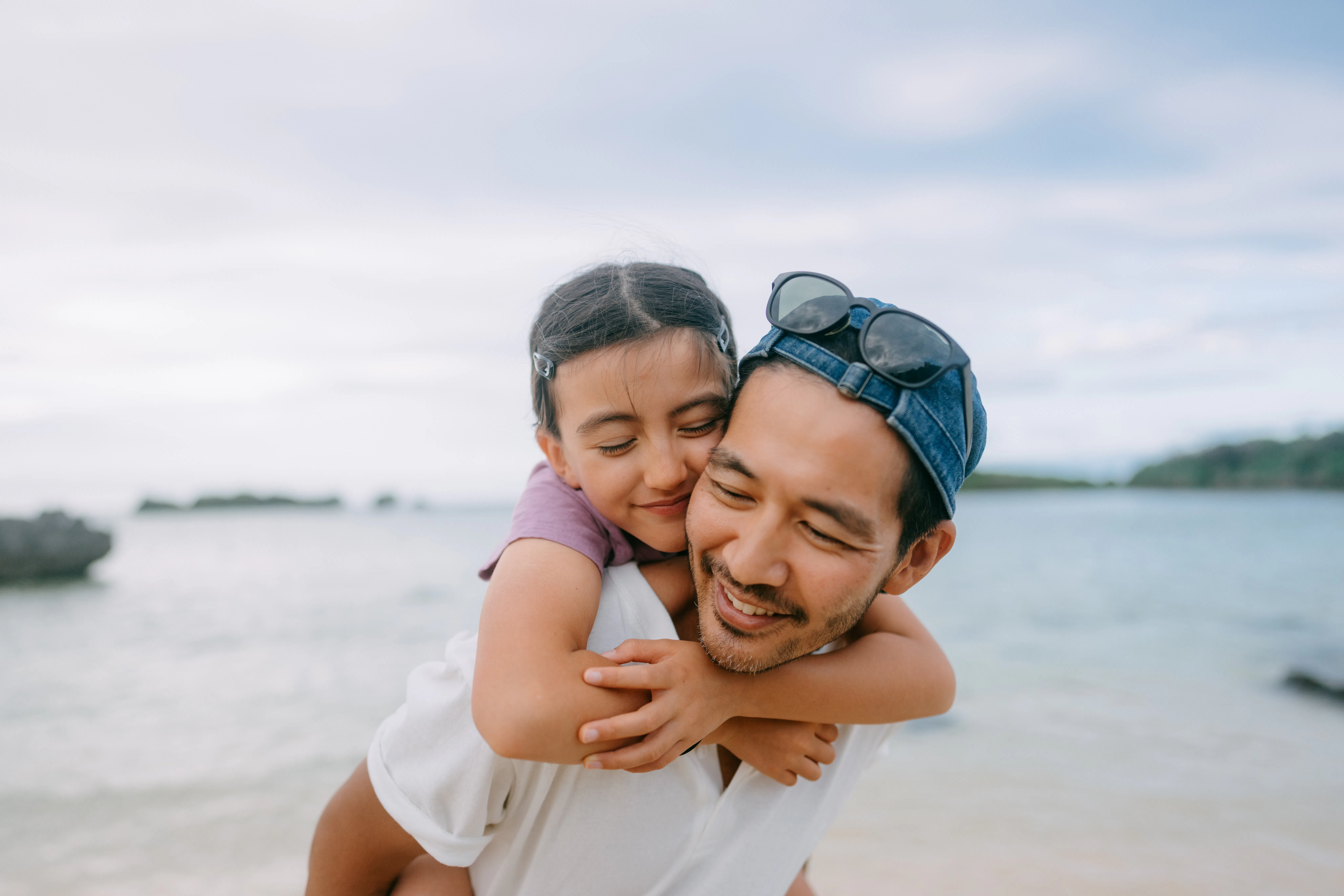 Close up of Japanese father and his young daughter having a good time on beach at dusk, Japan