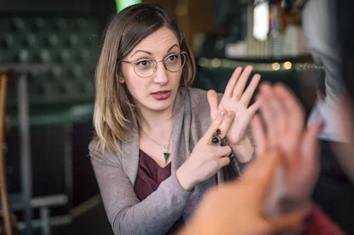 Two lovely women spending time enjoying coffee at the cafe and using sign language as a way of commu...