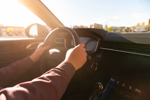 Person driving a modern car with hands on the steering wheel and a gps navigation map on the screen