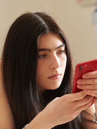 Teenage girl lying on her bed using a smart phone