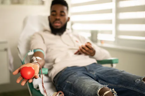 A male donor, lying down, shows the heart-shaped ball for blood donation at the modern blood donati...