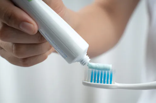 female squeezes toothpaste on the toothbrush