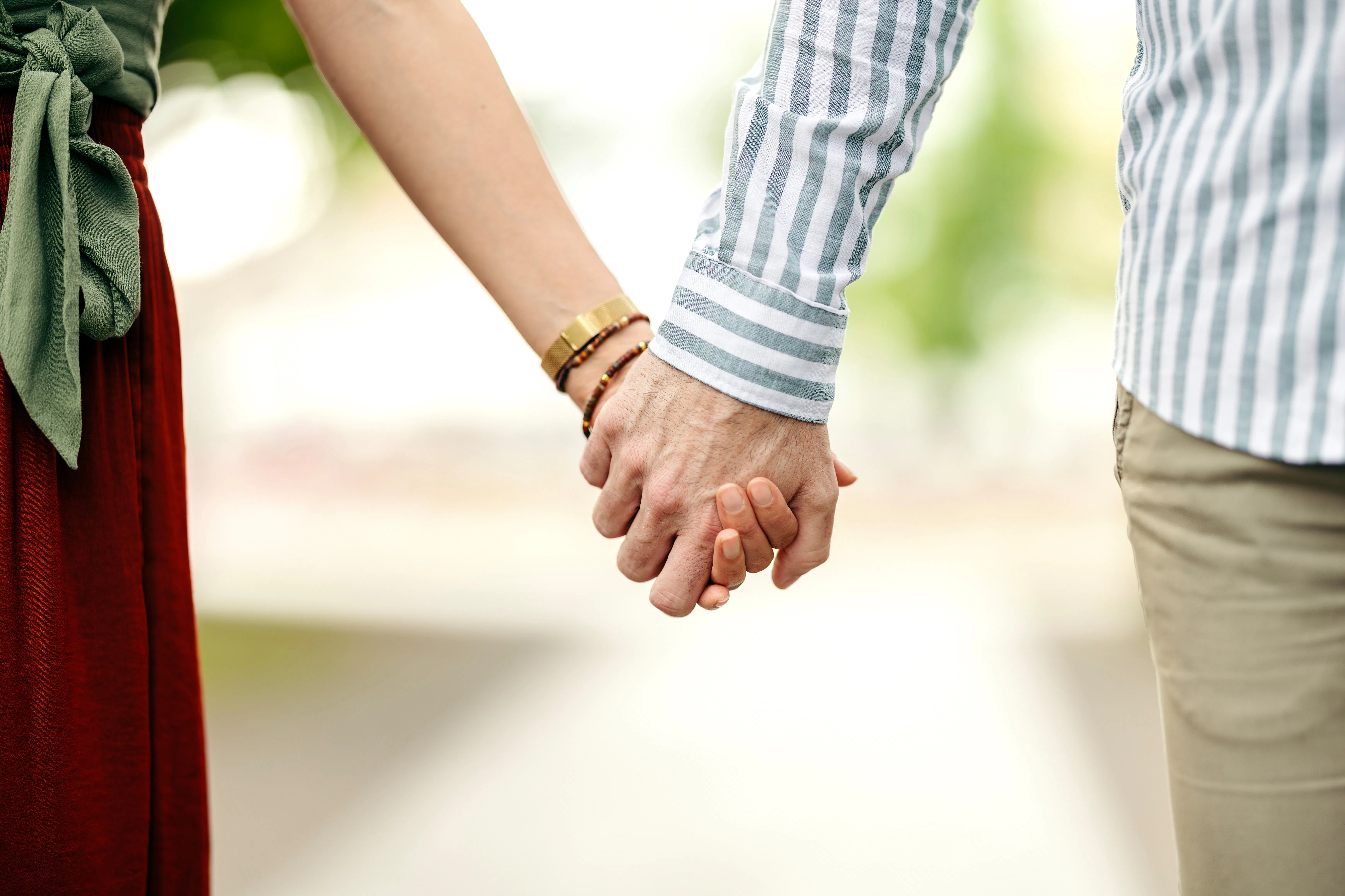 Two people standing close and holding hands, expressing connection, romance, and shared future, symb...