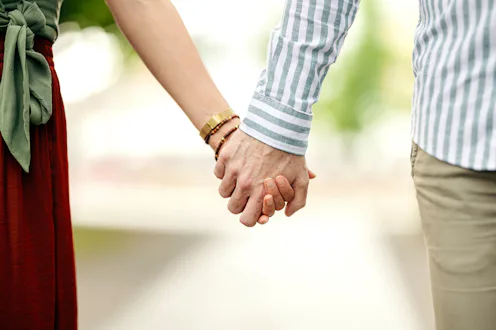 Two people standing close and holding hands, expressing connection, romance, and shared future, symb...
