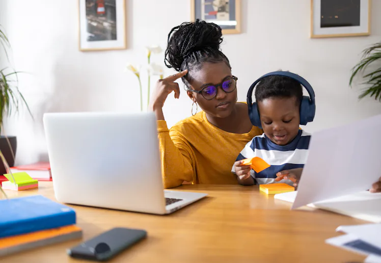 Young mother working from home and taking care of her son at the same time