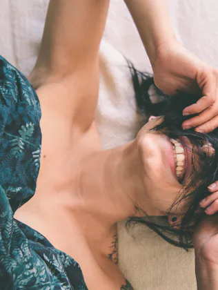 Tattooed young woman in bed having fun