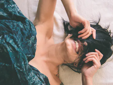 Tattooed young woman in bed having fun