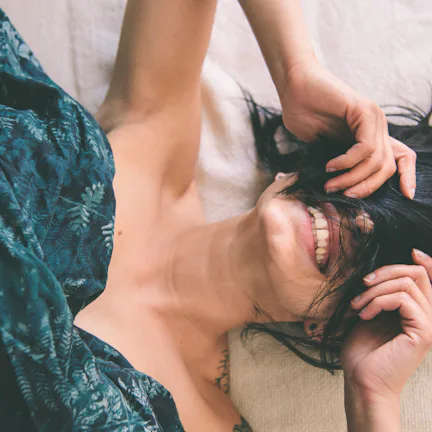 Tattooed young woman in bed having fun