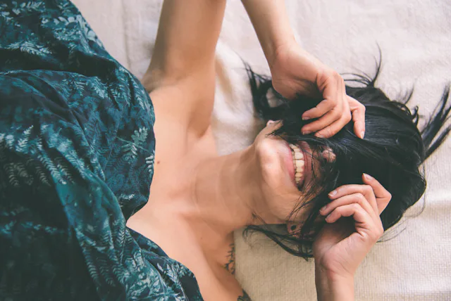 Tattooed young woman in bed having fun