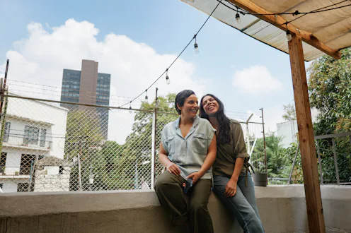 Two adult women enjoying friendship and conversation on an outdoor city balcony