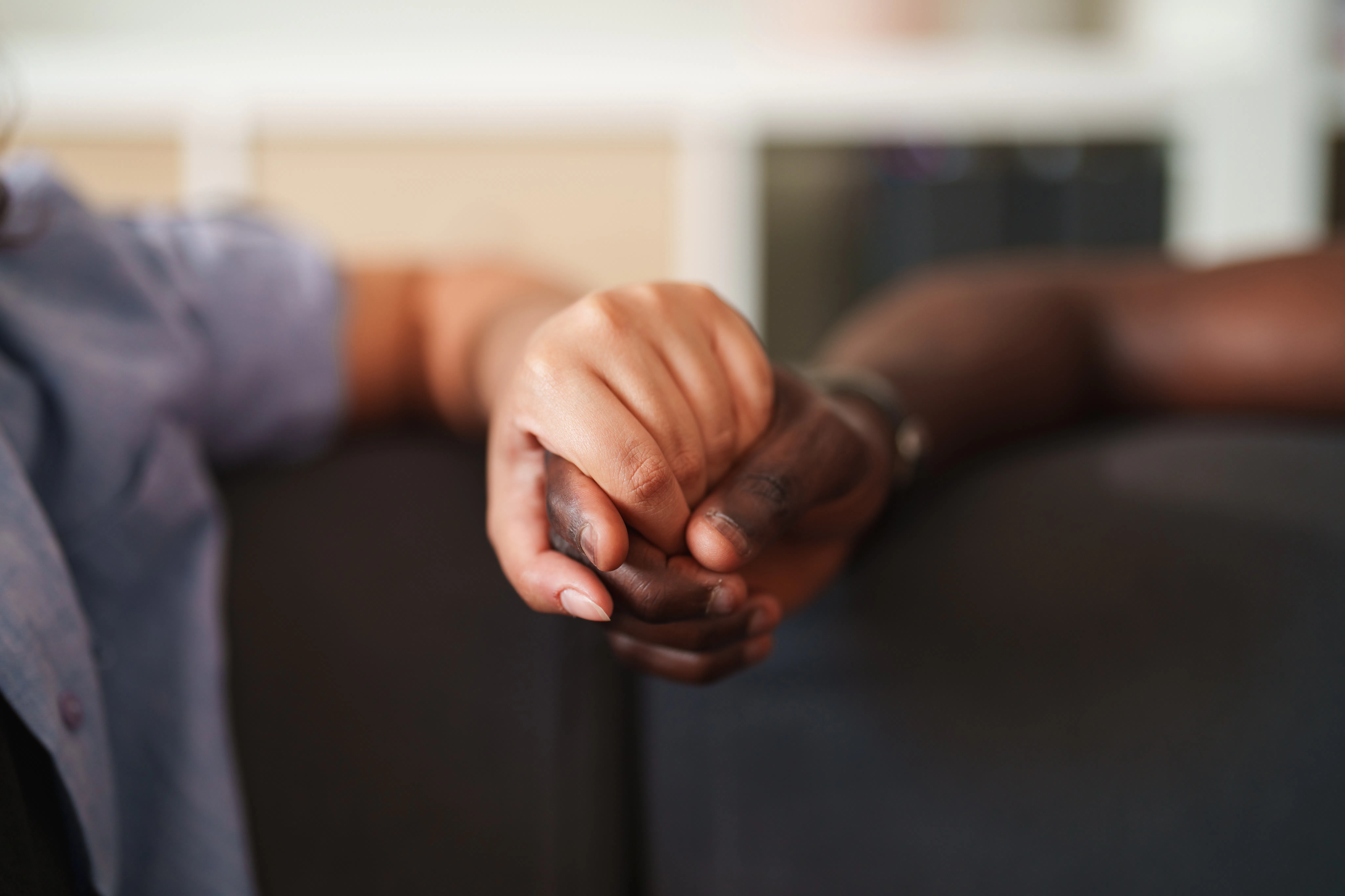 Close-up of a young interracial couple holding hands while spending time together at home. A quiet m...